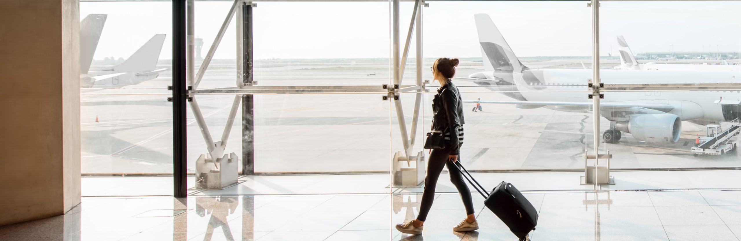 person carrying a suitcase at an airport to represent the costs of travel disruptions