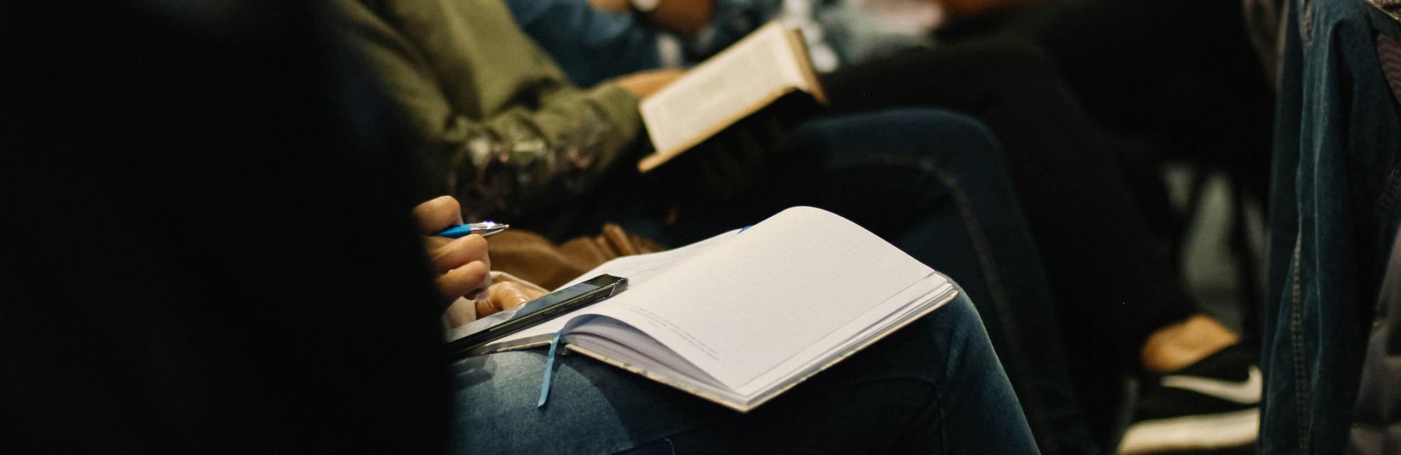 people sitting at a conference with. a notebook to represent finance events